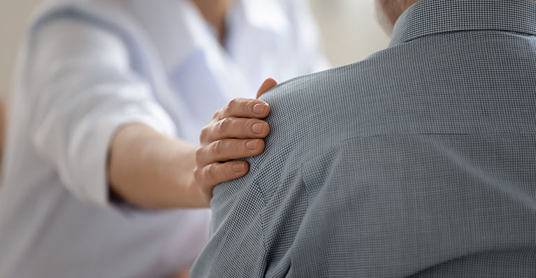 Woman with her hand on a mans shoulder showing empathy