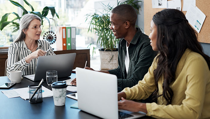 A woman helping a couple balance their budget in an office setting