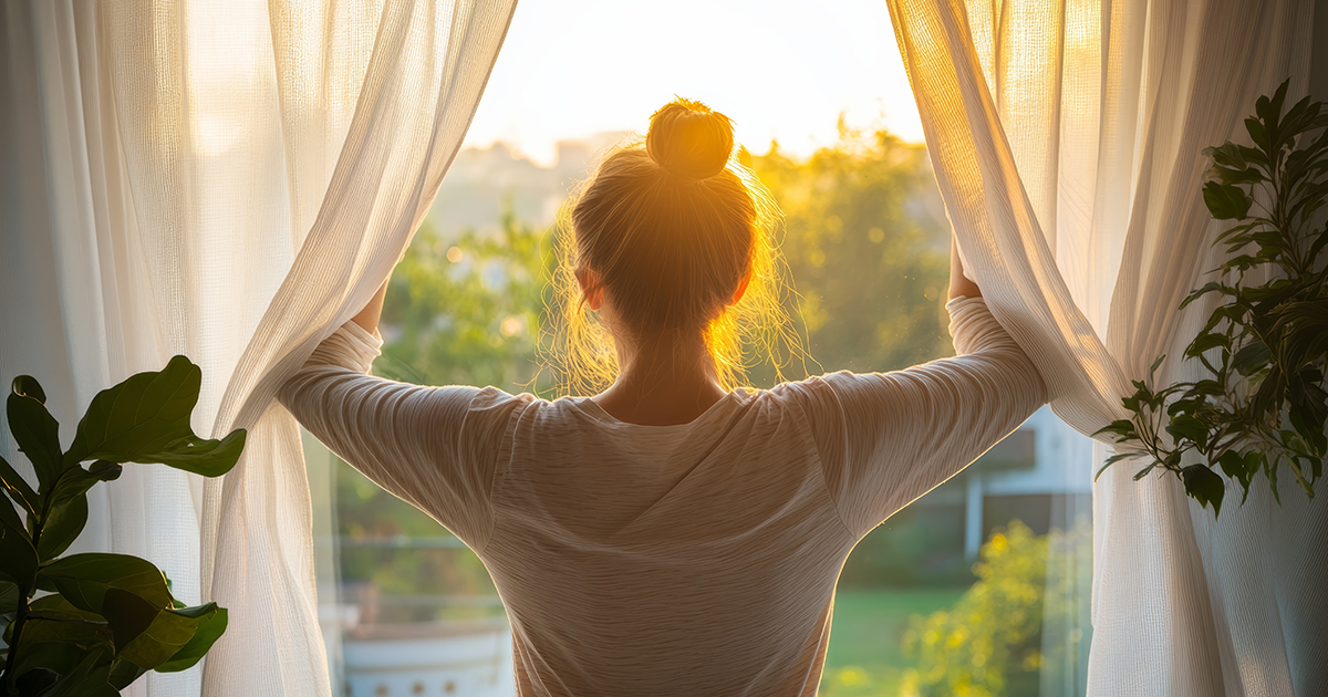 Woman looking out her window at a sunset