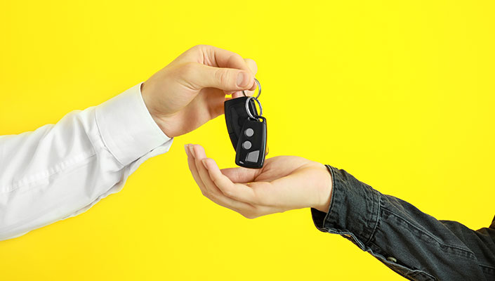 A person handing car keys to another person